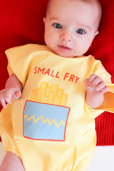 Baby wearing a yellow onesie with 'Small Fry' text and fries graphic on a red background