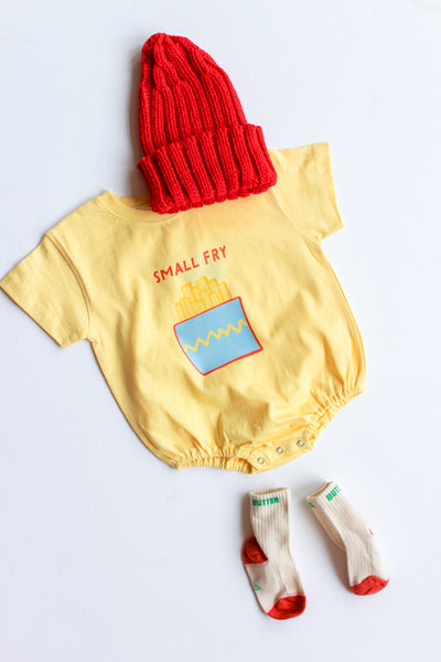 Yellow baby romper with 'Small Fry' print, red beanie, and socks on a light gray background