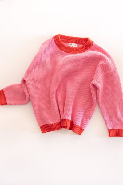 Pink sweater with red trim on a white background