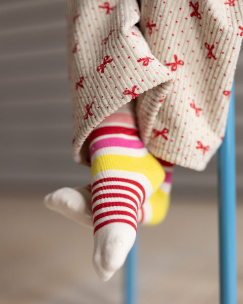 Child's legs wearing colorful socks and patterned pants with a blurred background