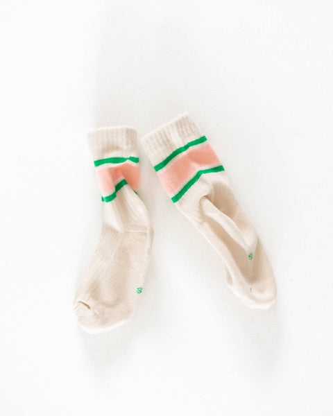 A pair of socks with horizontal watermelon stripe patterns in pink and green colors on a beige background.