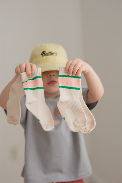A pair of socks with horizontal watermelon stripe patterns in pink and green colors on a beige background.