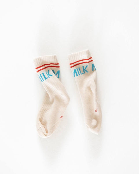 A pair of white crew socks with the word 'Milk' printed in blue, placed side by side against a white background.
