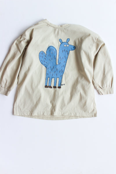 Beige long-sleeve shirt with a blue cartoon llama design on a white background
