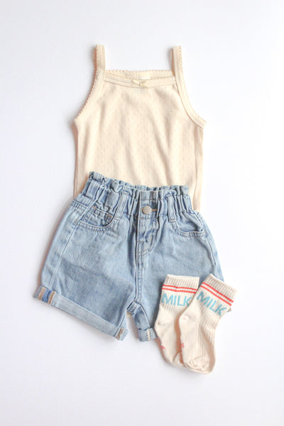 Children's outfit with tank top, denim shorts, and socks on a white background