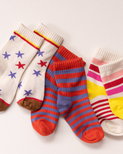 Three pairs of colorful socks with stars and stripe patterns on a white background.