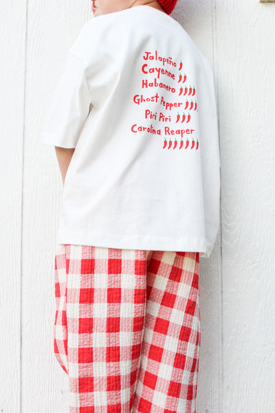 Back of white The Spicy One t-shirt with a hand-drawn list of pepper names and tiny pepper doodles