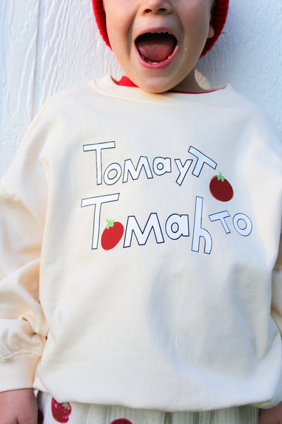 Kid wearing cream sweatshirt with hand-drawn Tomayto Tomahto lettering