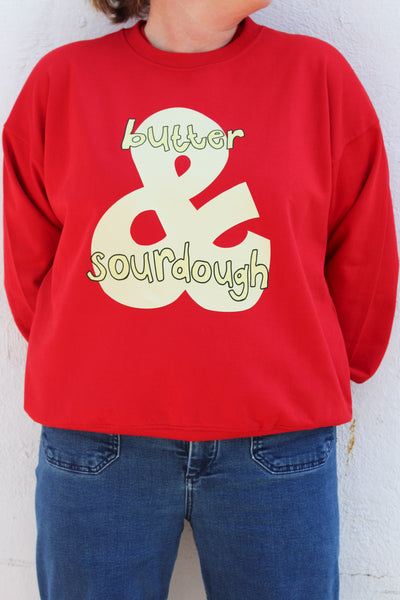 Woman wearing red cotton sweatshirt with a hand-drawn sourdough and butter graphic