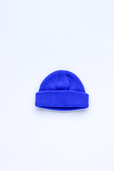 A bright royal blue knit beanie hat with a folded cuff, centered on a plain white background.