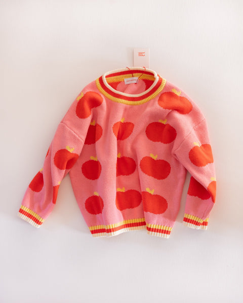 Pink sweater with red apple pattern on a white background
