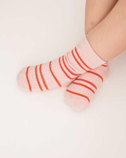 A pair of pink socks with red stripes, displayed against a white background.
