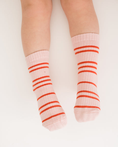 child wearing a pair of pink socks with red stripes, displayed against a white background.
