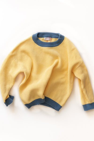 Yellow knit sweater with blue trim on a white background