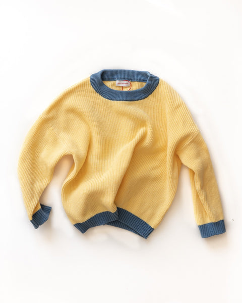 Yellow knit sweater with blue trim on a white background
