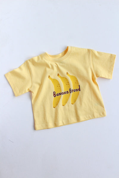 Yellow t-shirt with banana graphic and 'Banana Bread' text on a light gray background