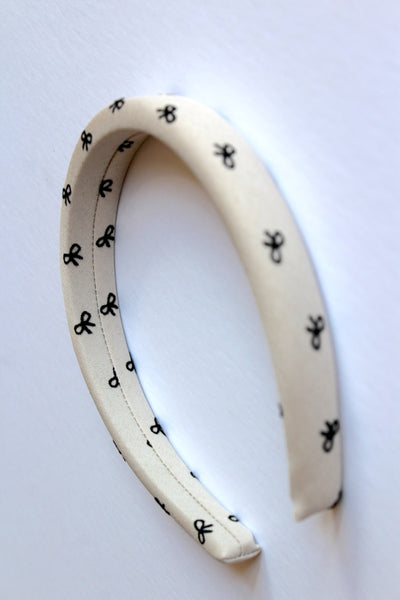 A close up of a beige headband with a ribbon print.