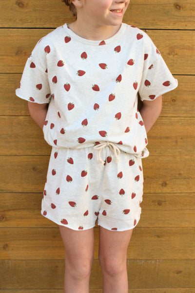 Child wearing a red strawberry short set 