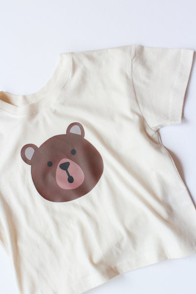 Beige t-shirt with a bear face design on a white background