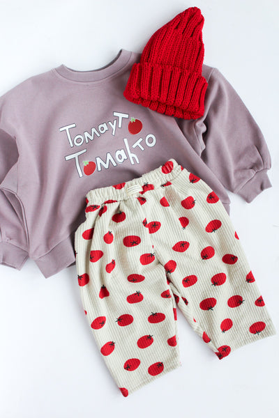 Purple sweatshirt with 'Tomato Tomato' text, red beanie, and red and white polka dot pants on a white background