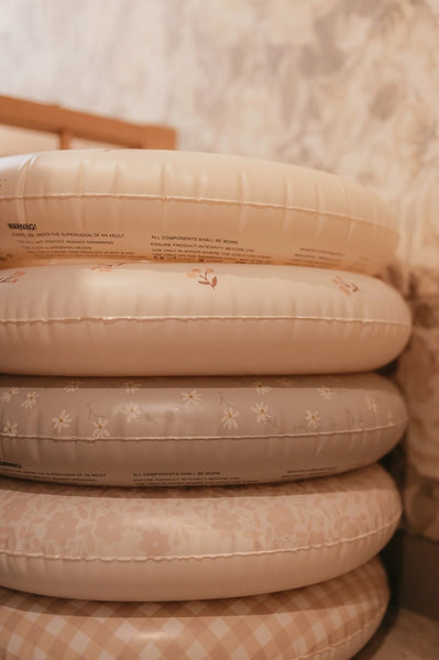 A stack of beige inflatable swim rings with a floral pattern.