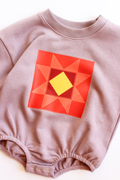 Baby romper with a red geometric pattern on a white background