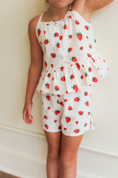 Child wearing a strawberry-patterned outfit against a plain background