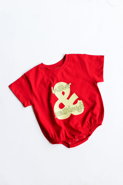 Red baby romper with yellow text on a white background
