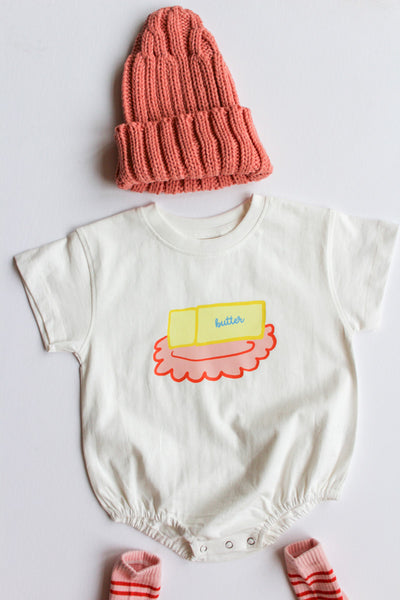 white romper for baby or toddler with a butter dish graphic matched with a pink beanie 