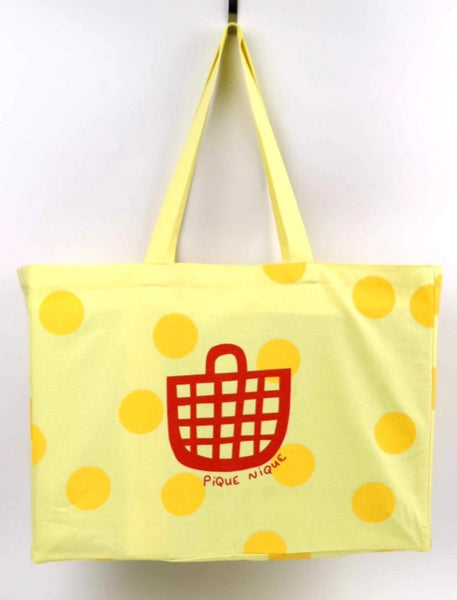 a yellow tote bag with red text that says pique nique and red basket 