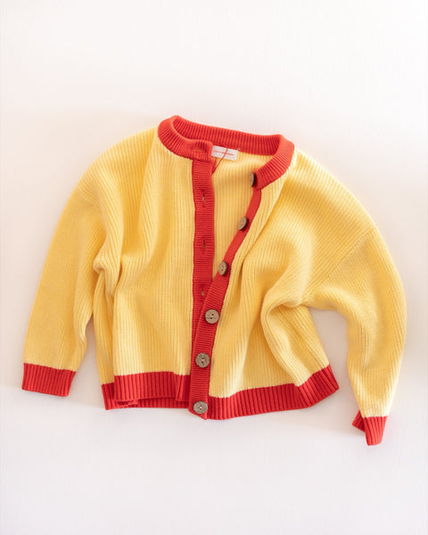 Yellow cardigan with red trim on a white background
