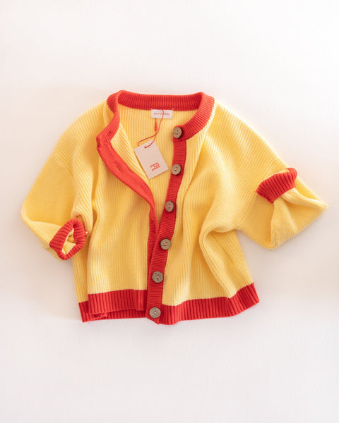 Yellow cardigan with red trim on a white background